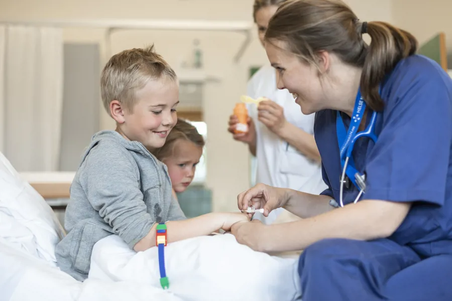 En gutt på sykehuset får innlagt venekanyle av helsepersonell.