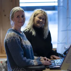 Kvinner som sitter ved et skrivebord med en bærbar datamaskin