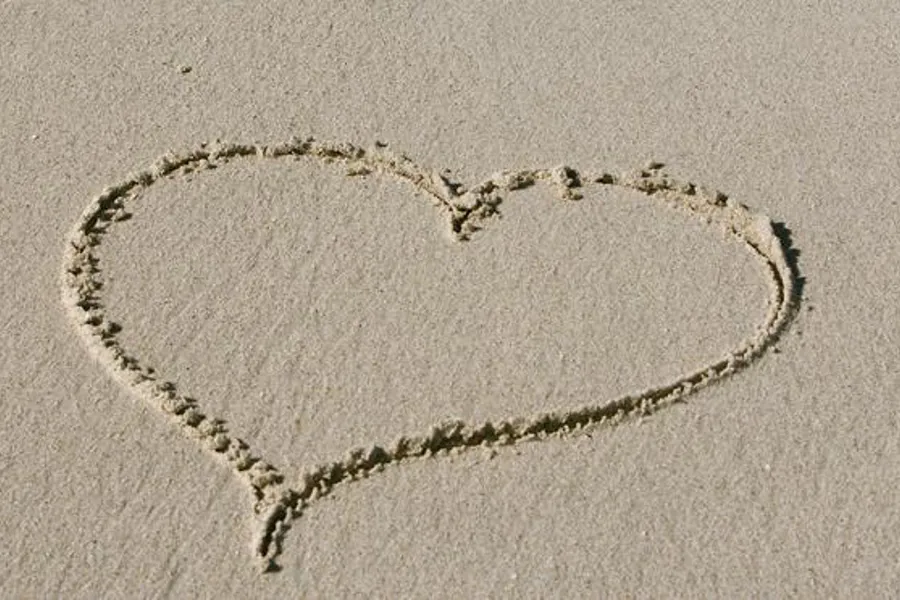 Hjerte tegnet i sand. Foto. 