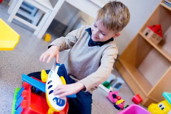 Elias leker på venterommet med et plastfly. Foto.