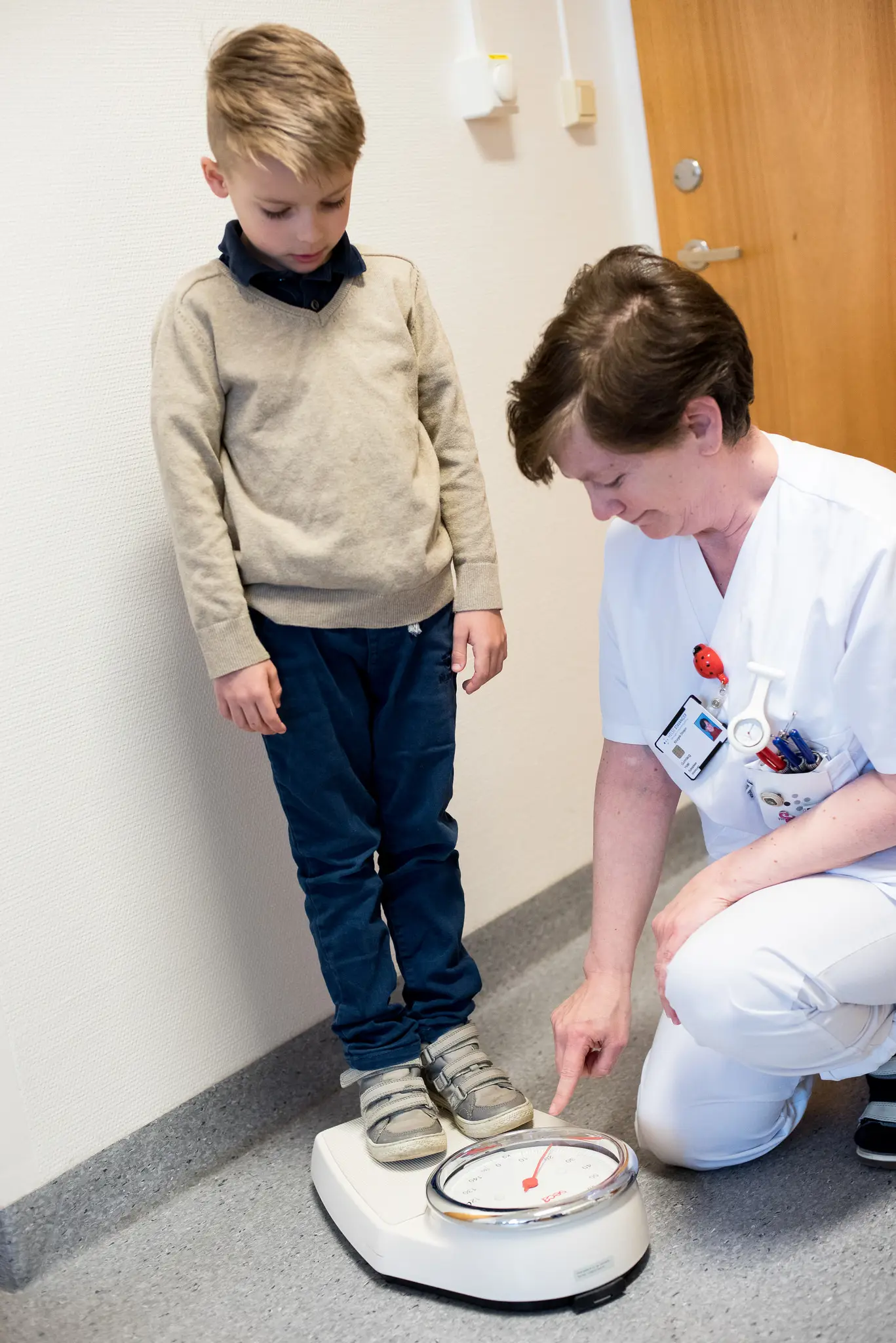 Elias veier seg på en vekt, ved hjelp av en sykepleier. Foto.