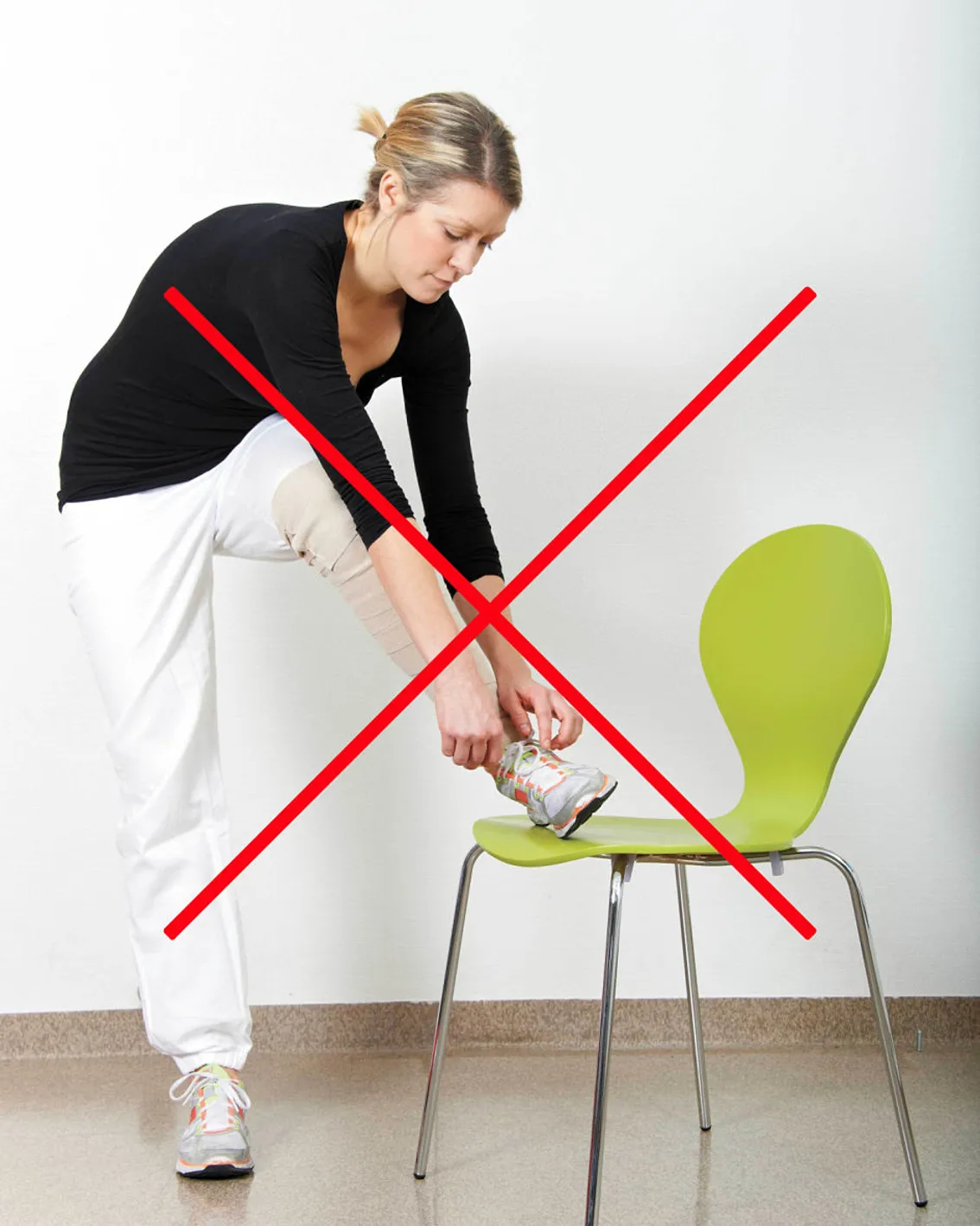 Pasient knyter skolisse stående med skoa plassert på en stol. Kneet peker inn mot midten. Skal unngås ved bakre tilgang. Foto.